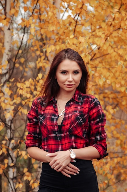 Retrato de mujer joven linda de apariencia eslava en ropa casual en otoño, en el campo con el telón de fondo de un parque de otoño. Bonita mujer caminando en el bosque en otoño dorado. Copia espacio