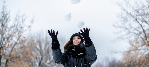 Retrato de mujer joven malabares con bolas de nieve en un día nevado de invierno al aire libre