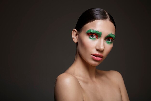 Retrato de mujer joven con maquillaje creativo rojo y verde brillante sobre fondo oscuro Moda de belleza