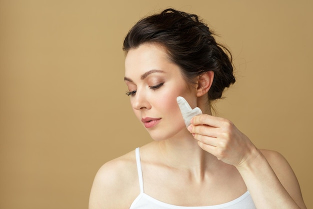 Retrato de una mujer joven con un masajeador facial de cuarzo rosa natural