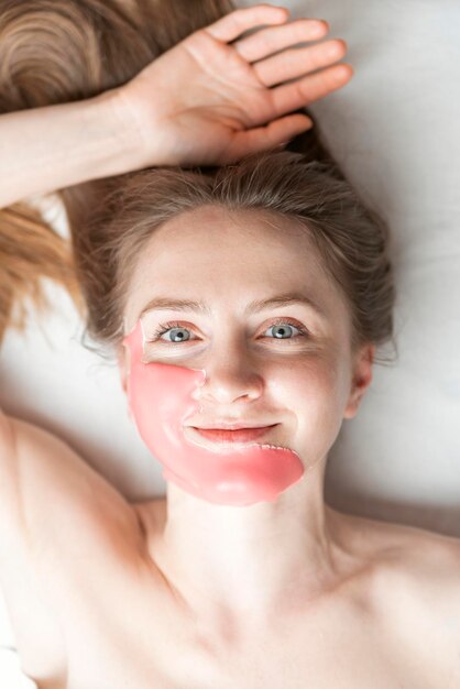 Retrato de mujer joven con máscara algínica en la cara en el salón de belleza Procedimiento cosmético para hacer que la piel sea más joven y fresca