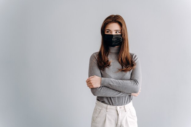 Retrato de una mujer joven con una máscara médica aislada sobre gris