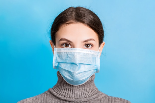 Retrato de mujer joven con máscara médica en azul. Protege tu salud. Concepto de coronavirus