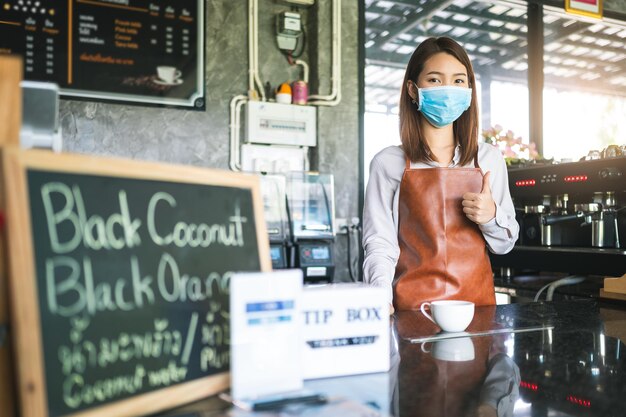 Foto retrato de una mujer joven con máscara de pie en un café