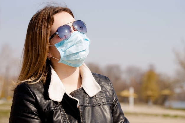 Retrato de una mujer joven en una máscara protectora y gafas de sol