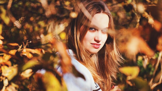 Retrato de una mujer joven en medio de los árboles durante el otoño