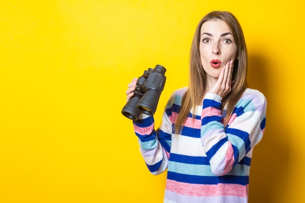 retrato mujer joven mira a través de binoculares