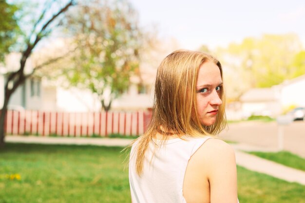 Foto retrato de una mujer joven mirando por encima del hombro en el campo