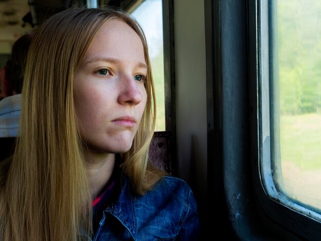 Foto retrato de una mujer joven mirando por la ventana