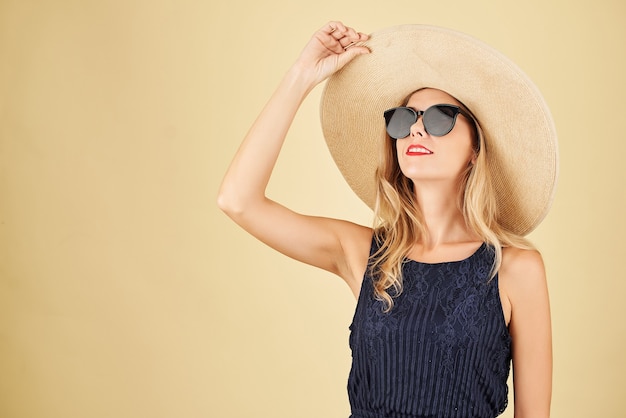 Retrato de mujer joven de moda elegante con sombrero de paja y gafas de sol mirando hacia arriba