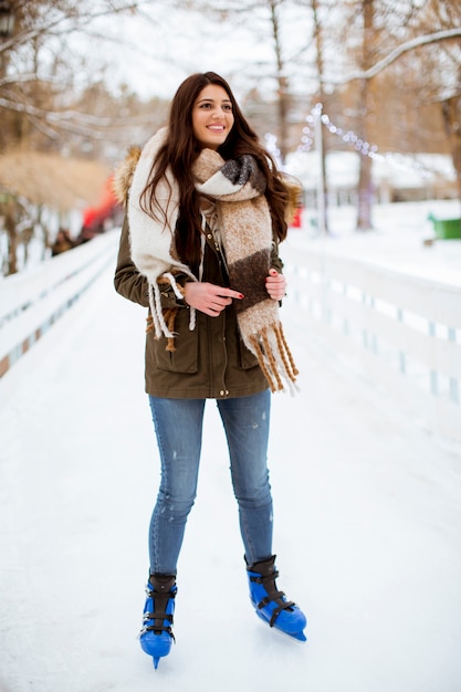 Retrato de mujer joven monta patines para hielo en el parque