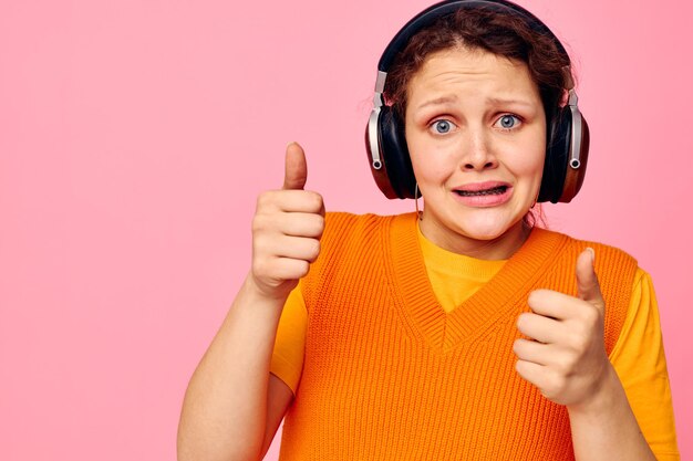 Retrato de una mujer joven mueca auriculares entretenimiento emociones música vista recortada inalterada