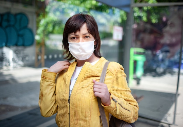 Retrato de una mujer joven no identificada con una máscara posando al aire libre durante una pandemia de coronovirus en un cálido día soleado de verano