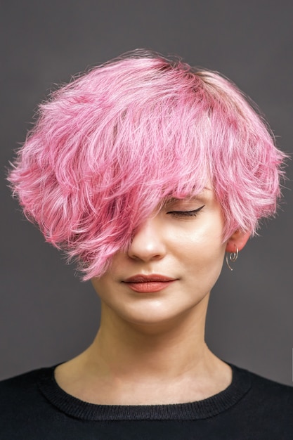 Retrato de una mujer joven con nuevo peinado corto de color rosa.