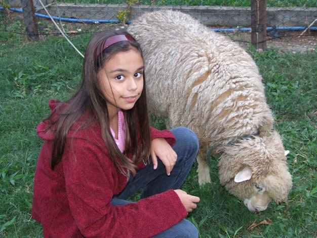 Foto retrato de una mujer joven con ovejas pastando en el campo