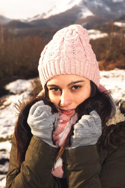 Retrato de mujer joven en un paisaje invernal bien envuelto para el frío