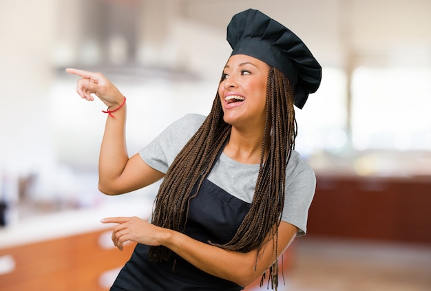 Retrato de una mujer joven panadero negro apuntando hacia el lado