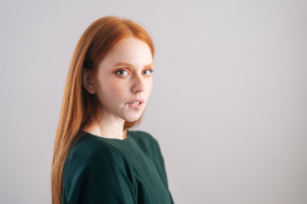 Retrato de mujer joven pelirroja atractiva modelo morderse el labio mirando a la cámara sobre fondo blanco.