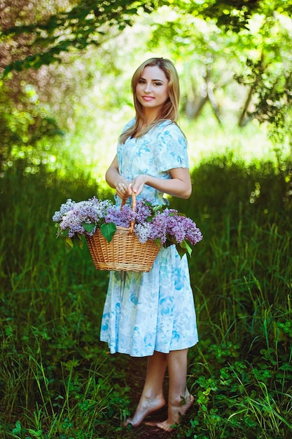 Retrato de mujer joven pelirroja en el jardín de primavera. pecas florecientes flores de color púrpura. Ramo de lilas