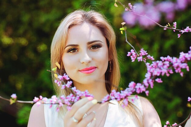 Retrato de mujer joven pelirroja en el jardín de primavera. pecas florecientes flores de color púrpura. Ramo de lilas