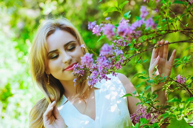 Retrato de mujer joven pelirroja en el jardín de primavera. pecas florecientes flores de color púrpura. Ramo de lilas