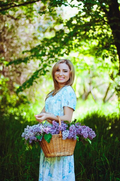 Retrato de mujer joven pelirroja en el jardín de primavera. pecas florecientes flores de color púrpura. Ramo de lilas
