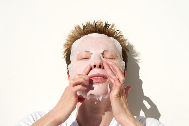 Retrato de mujer joven pelirroja con peinado lindo aplicar mascarilla facial de tejido en la cara