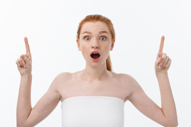 Retrato de mujer joven pelirroja con piel pecosa perfecta que muestra algo interesante en la pared del espacio de copia para su contenido publicitario.