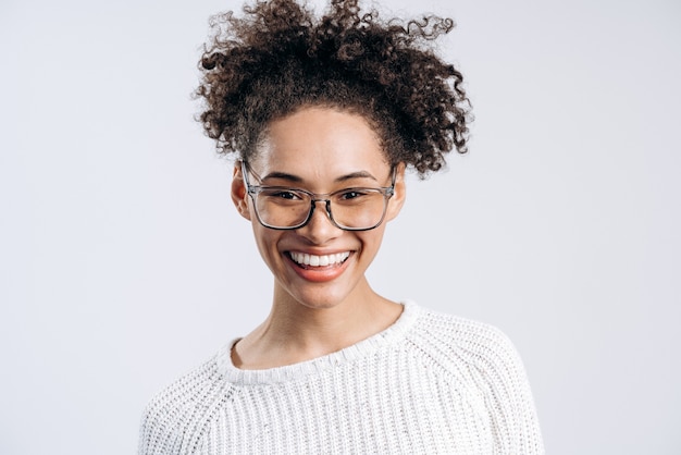 Retrato de mujer joven de pelo rizado emocionada de pie con cara feliz y sonriente. Foto de estudio en interiores, aislado sobre fondo blanco.