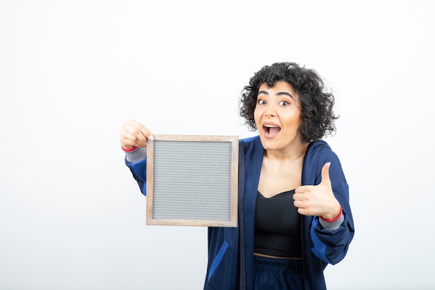 Retrato de una mujer joven con pelo rizado con marco de pie.