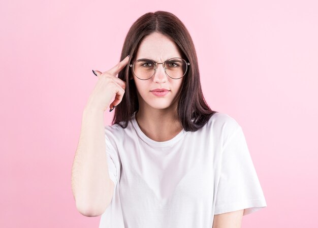 Retrato de mujer joven pensando con su dedo en la cabeza aislado sobre fondo de color rosa