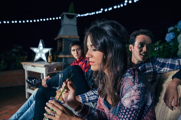 Foto retrato de mujer joven pensativa con cóctel con sus amigos en una fiesta al aire libre. concepto de amistad y celebraciones.