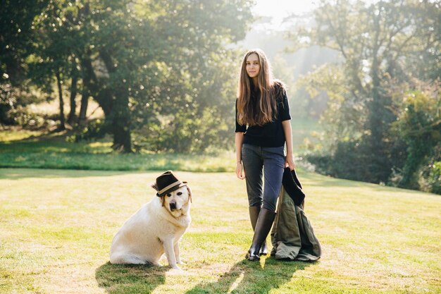 Foto retrato de una mujer joven con un perro contra los árboles