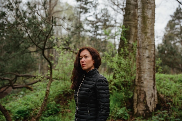 Foto retrato de una mujer joven de pie en el bosque