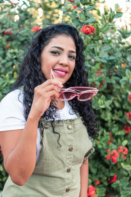 Un retrato de una mujer joven de pie en la calle sonriendo bajo el sol