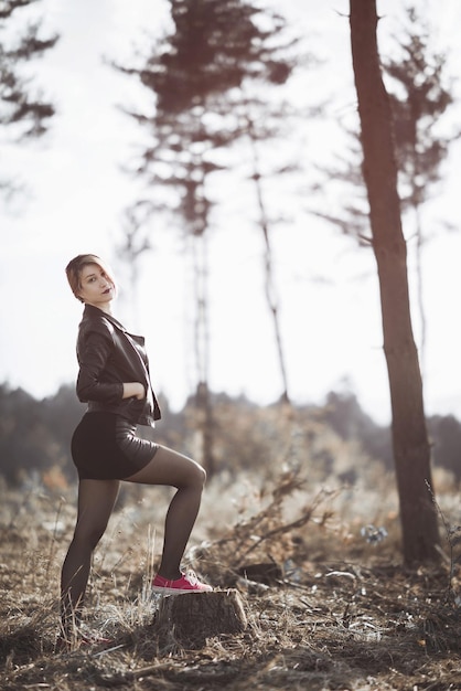 Foto retrato de una mujer joven de pie en el campo contra el cielo en el bosque