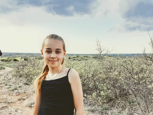 Foto retrato de una mujer joven de pie en el campo contra el cielo