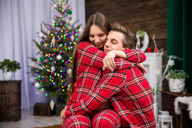 Foto retrato de una mujer joven de pie contra el árbol de navidad