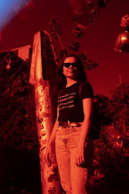 Foto retrato de una mujer joven de pie contra los árboles y el cielo