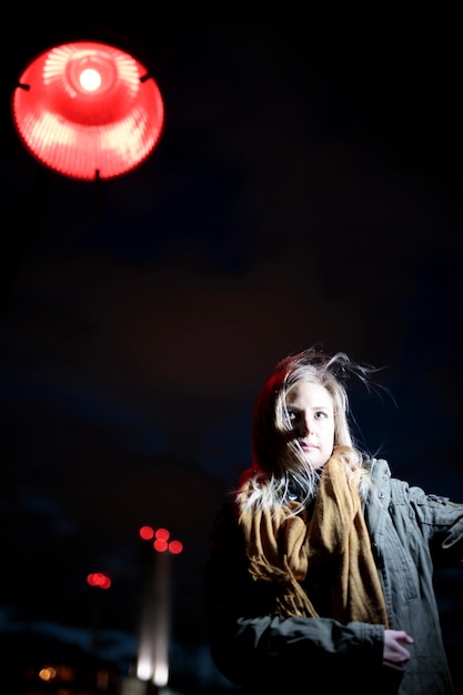Foto retrato de una mujer joven de pie contra la ciudad iluminada por la noche