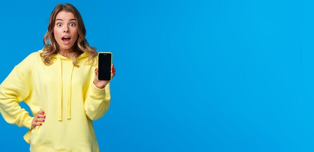 Foto retrato de una mujer joven de pie contra un fondo azul