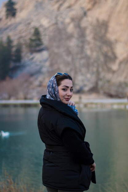 Foto retrato de una mujer joven de pie contra el lago