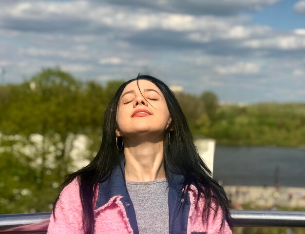 Foto retrato de una mujer joven de pie contra el lago