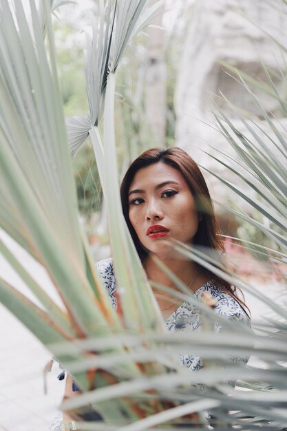 Retrato de una mujer joven de pie contra las plantas en el parque