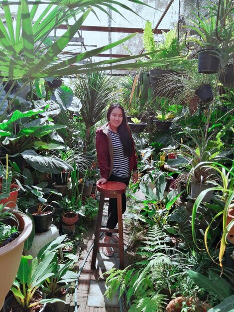 Foto retrato de una mujer joven de pie contra las plantas