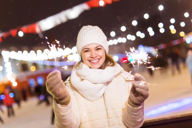 Foto retrato de una mujer joven de pie frente a la navidad iluminada