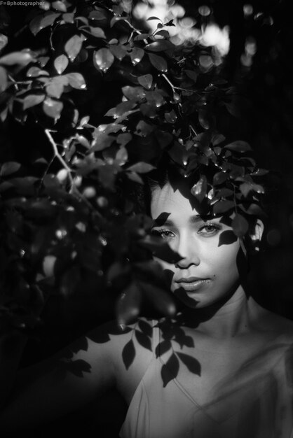 Foto retrato de una mujer joven de pie junto a una planta por la noche