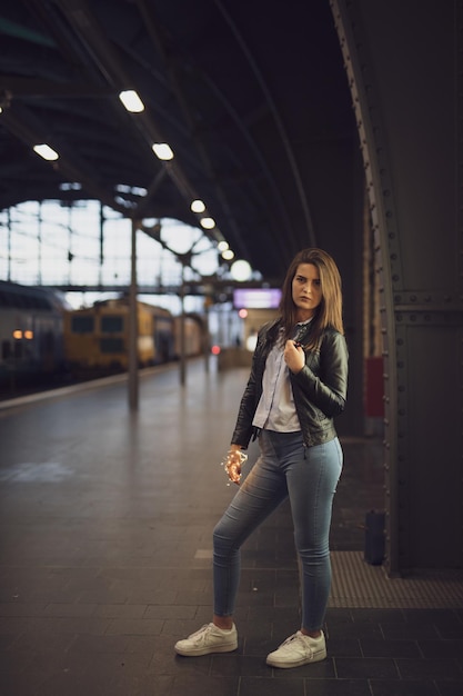 Foto retrato de una mujer joven de pie en la plataforma de la estación de tren