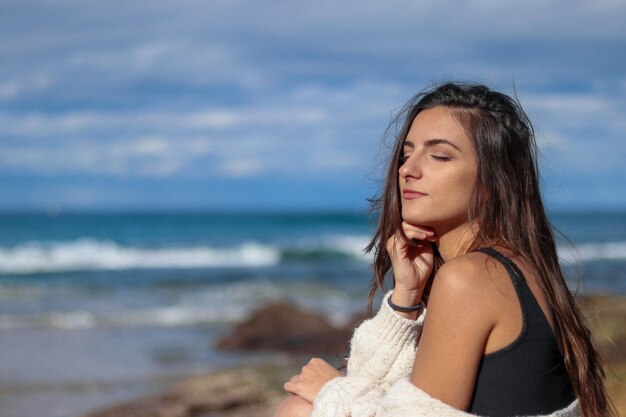 Foto retrato de una mujer joven de pie en la playa contra el cielo