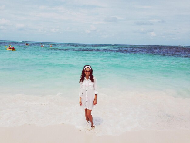 Foto retrato de una mujer joven de pie en la playa